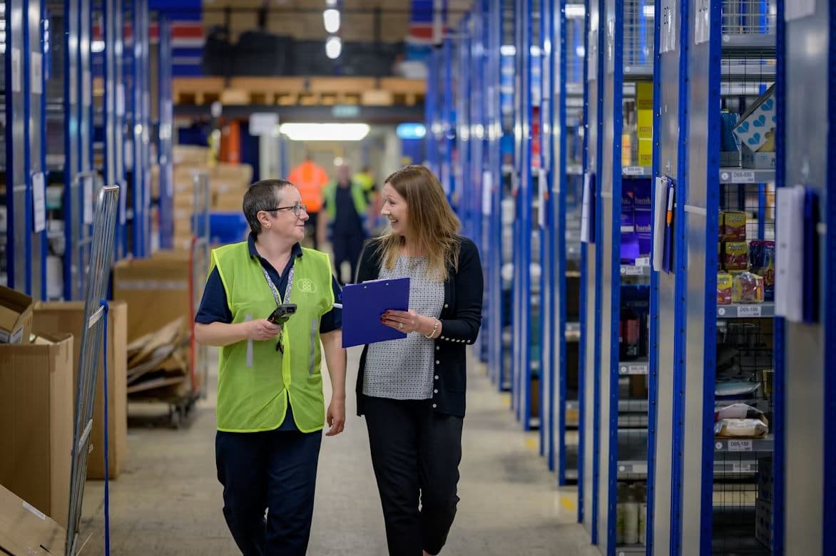Two inventory professionals reviewing stock in a warehouse aisle